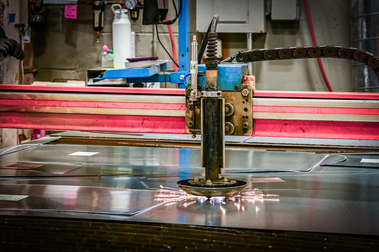 A close-up of an industrial cutting machine emitting sparks as it slices through a sheet of metal in a factory setting, where Building Information Modeling ensures precision and efficiency in the manufacturing process.